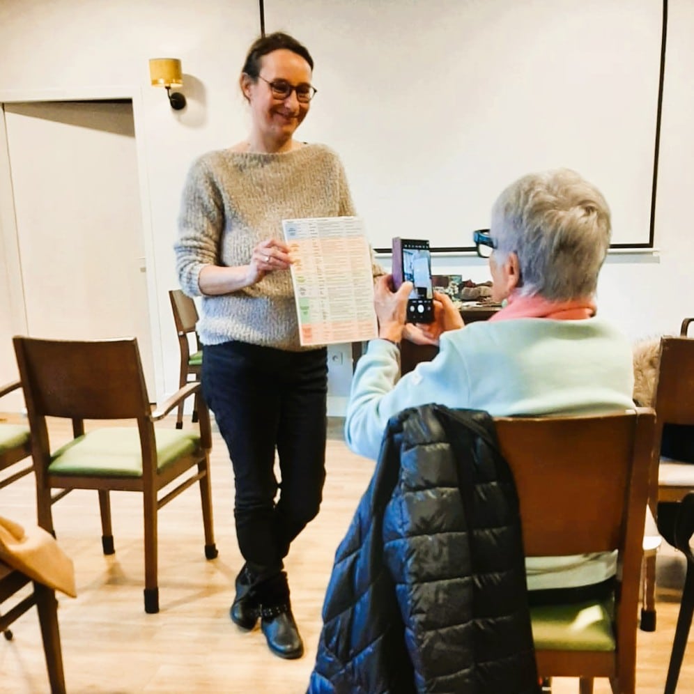 Senior découvrant les fleurs de Bach et leurs bienfaits lors d'une conférence dans sa résidence.